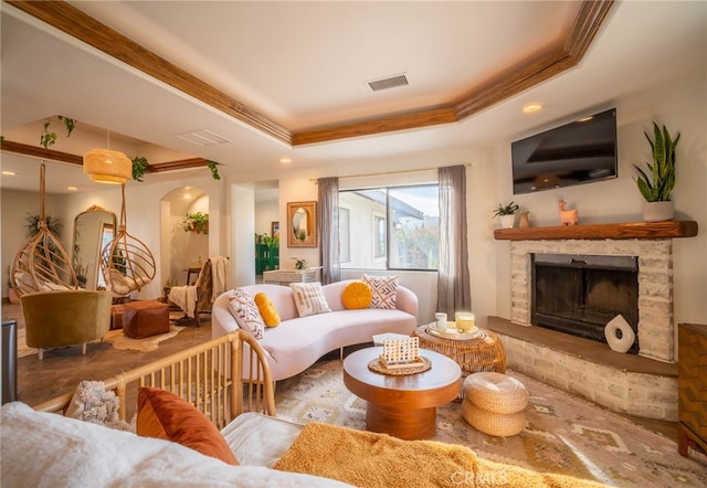 living room with a stone fireplace and a raised ceiling