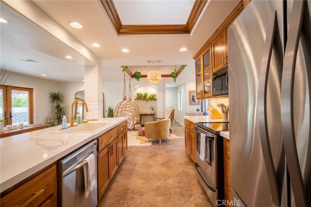 kitchen featuring a raised ceiling, ornamental molding, sink, decorative light fixtures, and stainless steel appliances