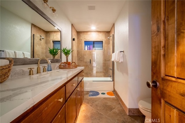 full bathroom with bath / shower combo with glass door, vanity, tile patterned flooring, and toilet