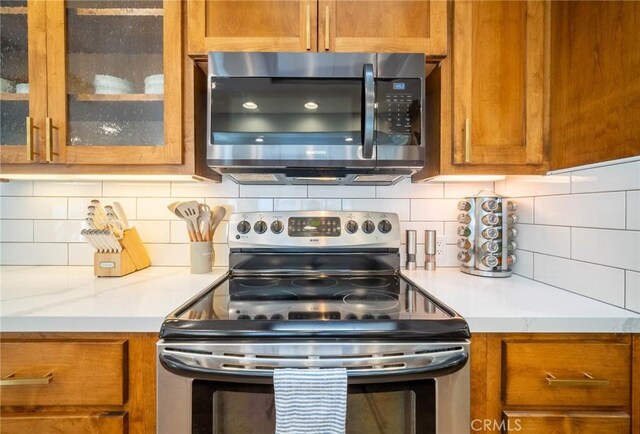 kitchen with light stone counters, stainless steel appliances, and tasteful backsplash