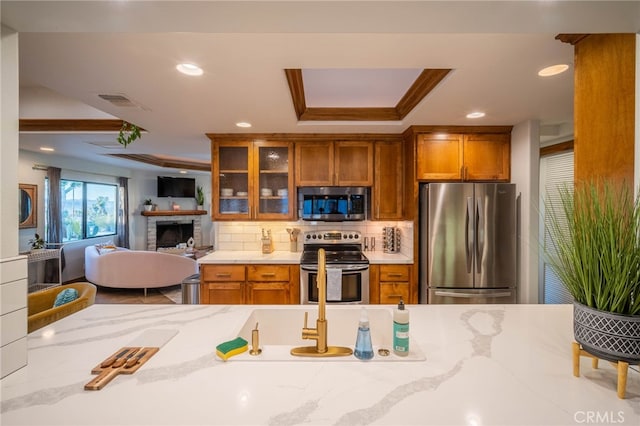 kitchen with ornamental molding, appliances with stainless steel finishes, light stone countertops, and tasteful backsplash