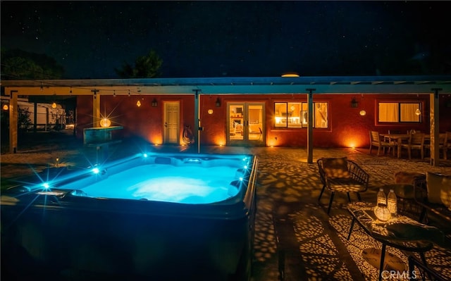 pool at twilight featuring a patio and a hot tub