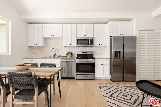 kitchen with light hardwood / wood-style floors, sink, stainless steel appliances, and white cabinets