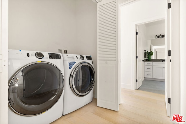 clothes washing area with separate washer and dryer and light hardwood / wood-style floors