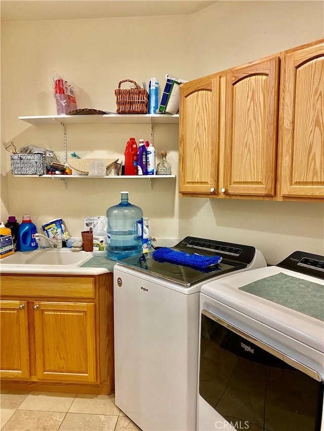 clothes washing area featuring separate washer and dryer, sink, light tile patterned flooring, and cabinets