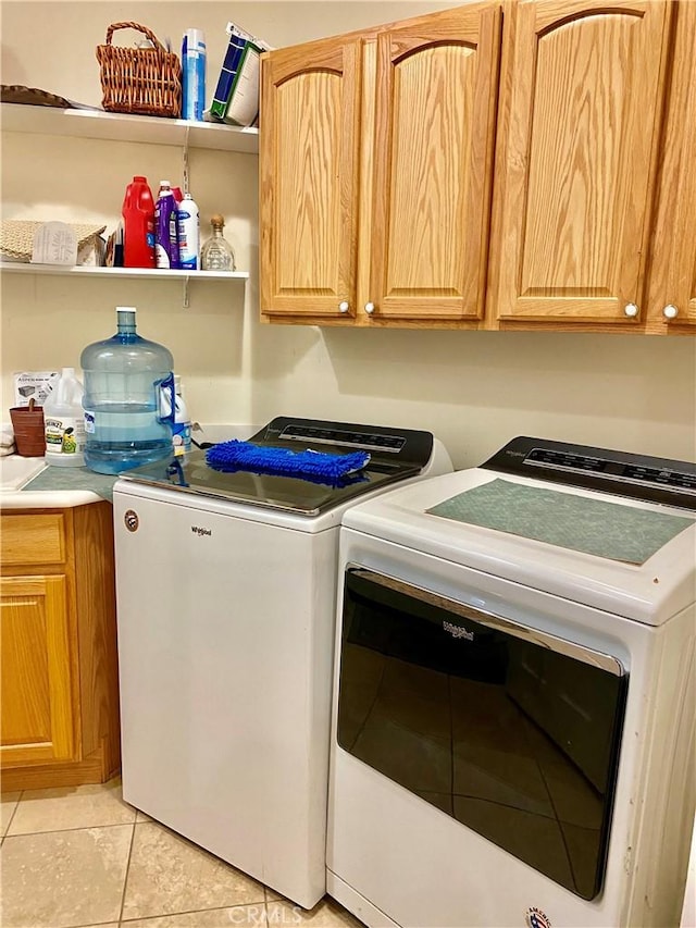 washroom featuring washing machine and dryer, light tile patterned floors, and cabinets