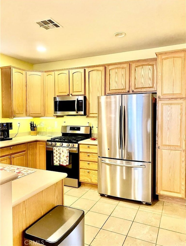 kitchen featuring appliances with stainless steel finishes, light brown cabinetry, and light tile patterned flooring