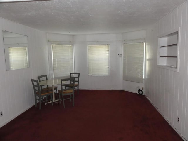 dining space with dark carpet and a textured ceiling