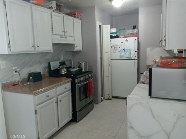 kitchen featuring white cabinets, stainless steel gas stove, and white fridge