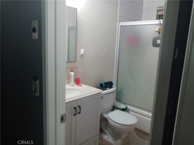 full bathroom with bath / shower combo with glass door, vanity, and toilet