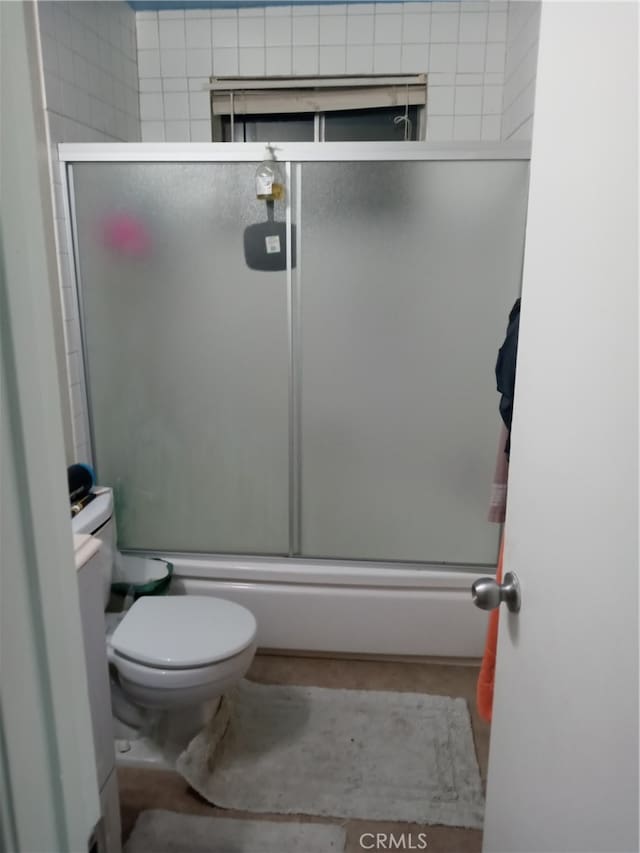 bathroom with enclosed tub / shower combo and toilet