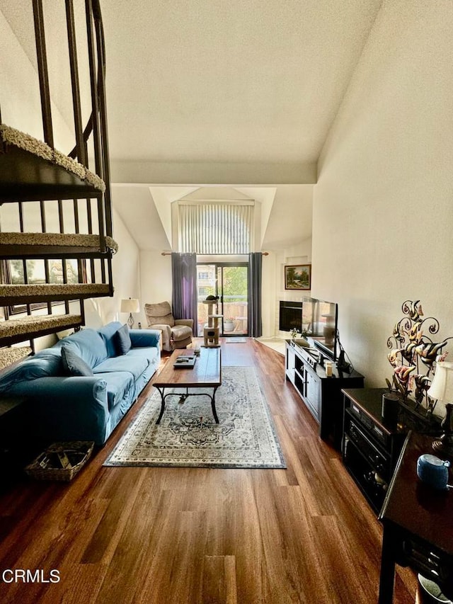 living room with wood-type flooring, a textured ceiling, and vaulted ceiling