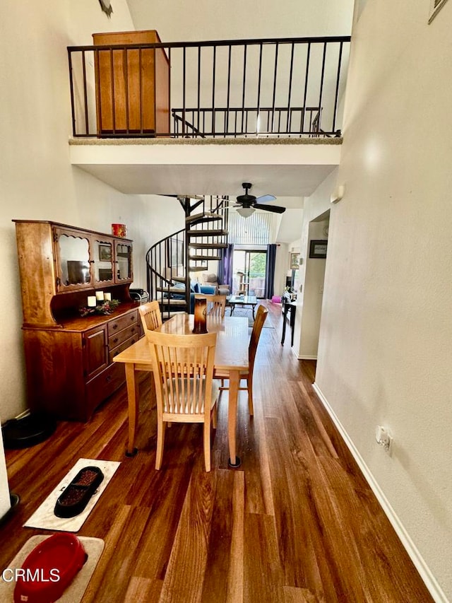 dining space with ceiling fan, a towering ceiling, and dark hardwood / wood-style flooring