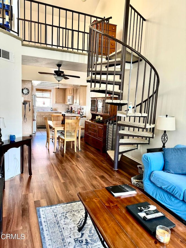 living room featuring wood-type flooring, a towering ceiling, and ceiling fan