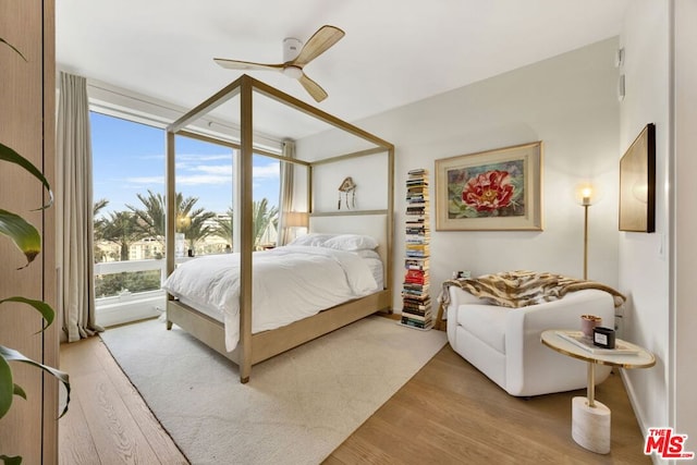 bedroom with ceiling fan, light hardwood / wood-style floors, multiple windows, and floor to ceiling windows