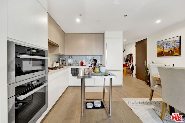 kitchen with stainless steel appliances, light wood-type flooring, white cabinetry, and tasteful backsplash