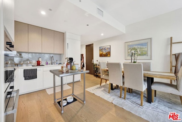 kitchen with gray cabinets, wall oven, decorative backsplash, sink, and light hardwood / wood-style flooring