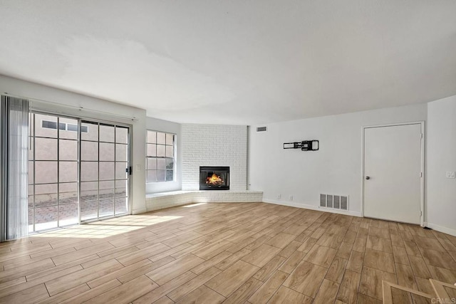 unfurnished living room with a fireplace, light hardwood / wood-style flooring, and plenty of natural light