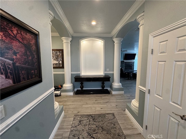 hallway featuring decorative columns, light hardwood / wood-style floors, and crown molding