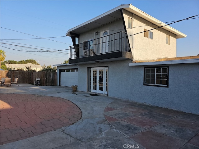 rear view of property featuring a balcony, a patio, and french doors