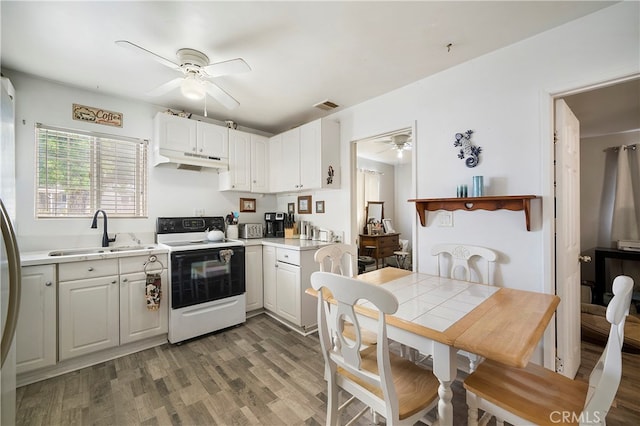 kitchen with ceiling fan, electric stove, and white cabinetry