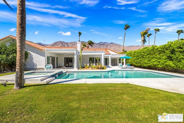 back of house featuring a mountain view, a pool with hot tub, a patio area, and a yard