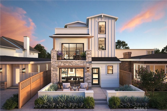 back house at dusk with outdoor lounge area, a patio area, and a balcony