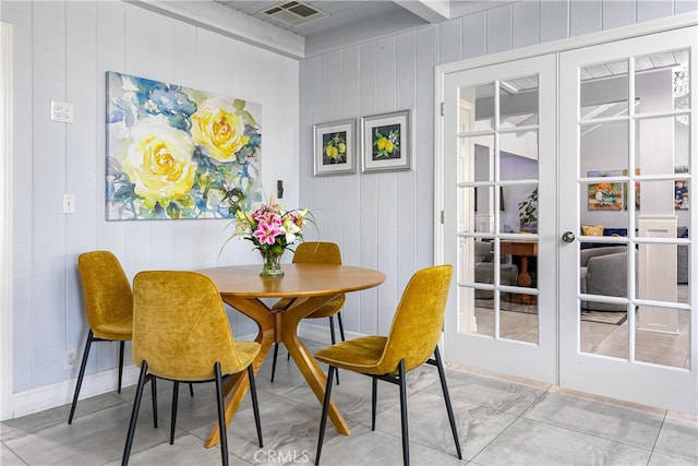 dining space with french doors and wood walls