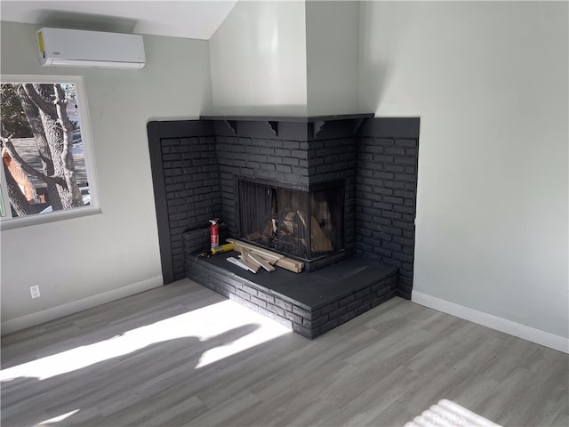 room details with wood-type flooring, a brick fireplace, and a wall unit AC