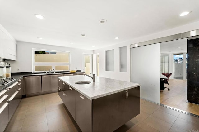 kitchen featuring white cabinetry, sink, an island with sink, wood-type flooring, and appliances with stainless steel finishes