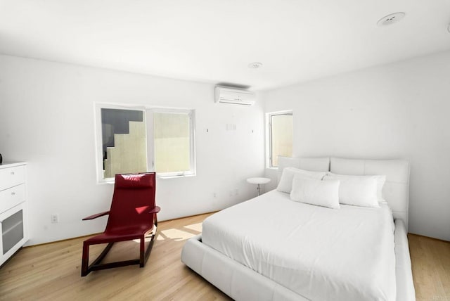 bedroom with light wood-type flooring and a wall unit AC