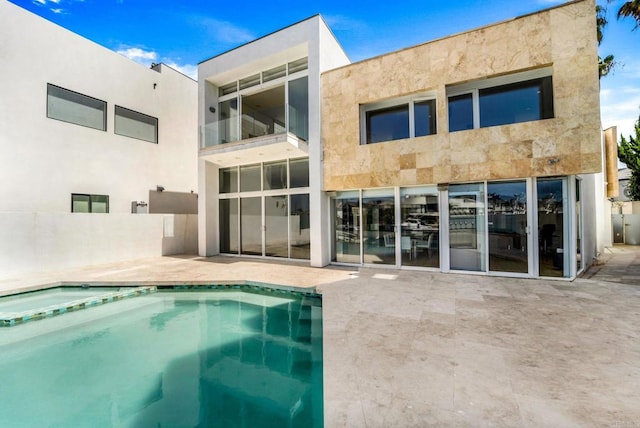 rear view of house with a pool with hot tub