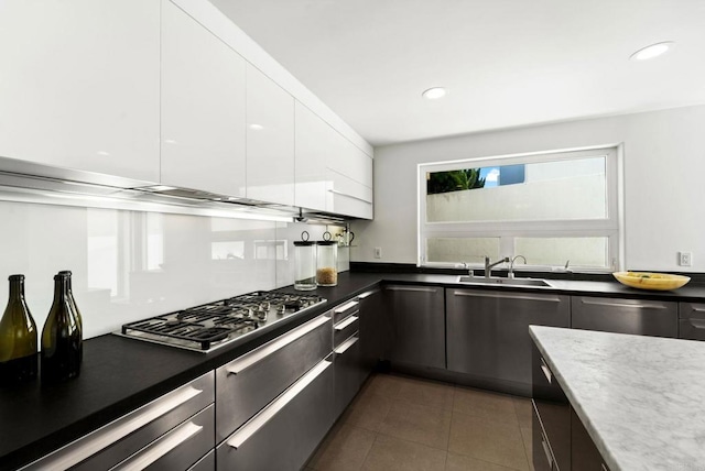 kitchen with stainless steel appliances, white cabinetry, dark tile patterned floors, and sink