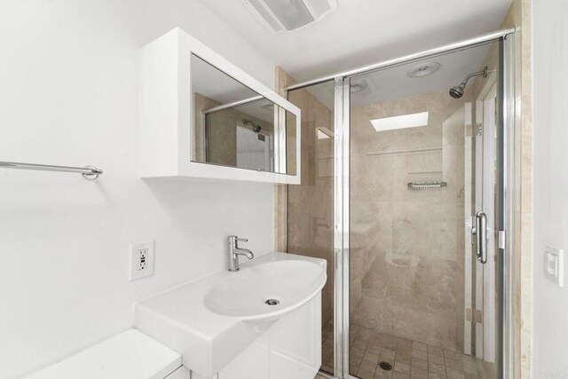 bathroom featuring a shower with door and sink