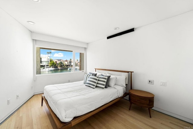 bedroom featuring light hardwood / wood-style floors and a water view