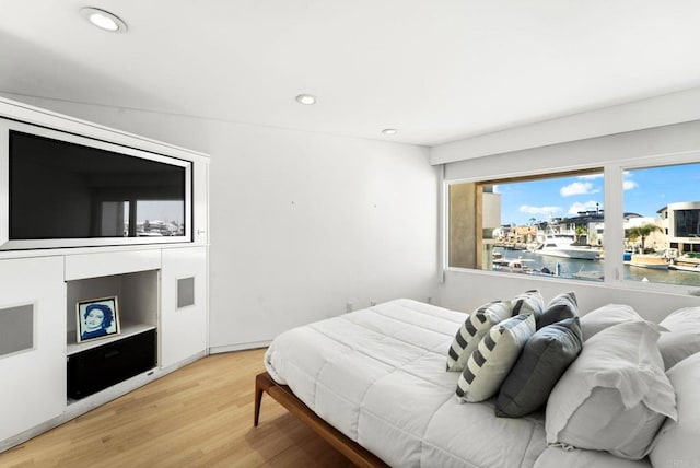 bedroom with wood-type flooring and a water view