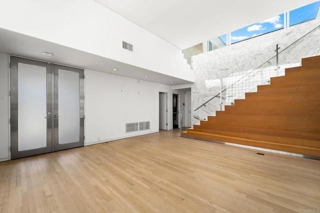 interior space featuring french doors, a towering ceiling, and light hardwood / wood-style floors