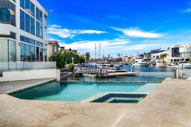 view of pool with an in ground hot tub, a water view, and pool water feature