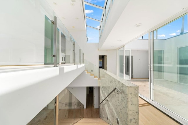 interior space with wood-type flooring, a towering ceiling, and a healthy amount of sunlight