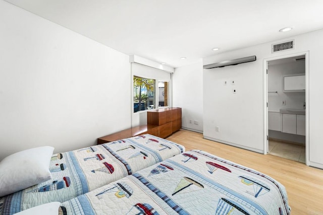 bedroom with connected bathroom and hardwood / wood-style flooring