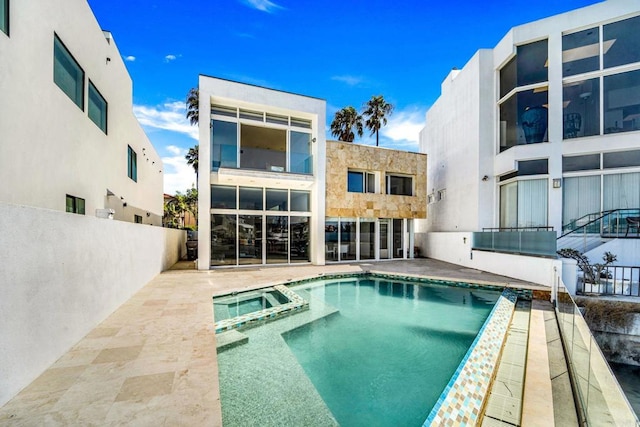 rear view of property featuring a pool with hot tub and a patio area