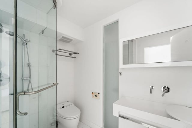 bathroom featuring vanity, toilet, and a shower with shower door