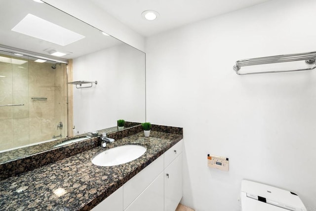 bathroom featuring a skylight, toilet, vanity, and walk in shower