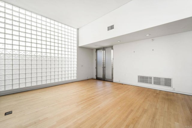 unfurnished room featuring light hardwood / wood-style floors and a towering ceiling