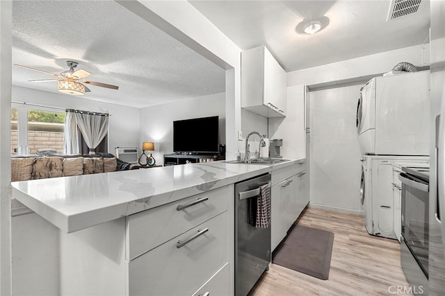 kitchen featuring ceiling fan, light hardwood / wood-style flooring, white cabinetry, dishwasher, and stacked washer / drying machine