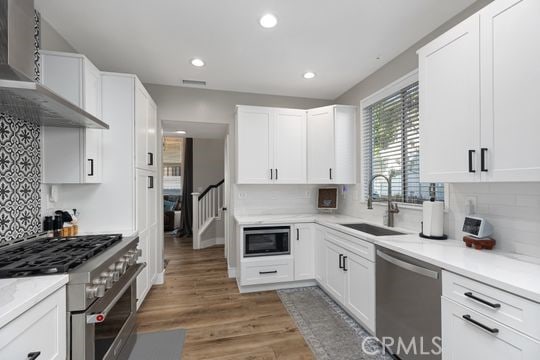 kitchen featuring sink, dark hardwood / wood-style flooring, stainless steel appliances, white cabinets, and wall chimney exhaust hood