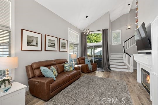 living room featuring lofted ceiling, a chandelier, and light hardwood / wood-style flooring