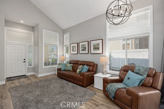 living room with light wood-type flooring, a healthy amount of sunlight, and a notable chandelier