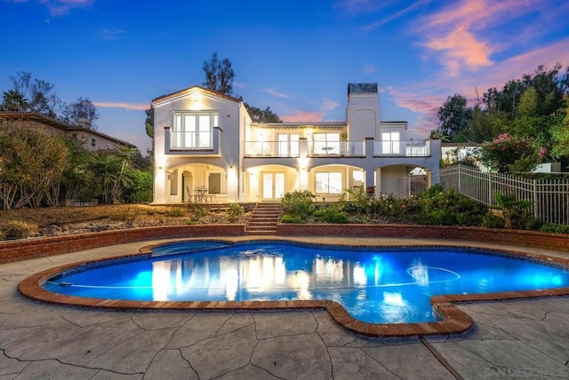 pool at dusk with a patio and an in ground hot tub