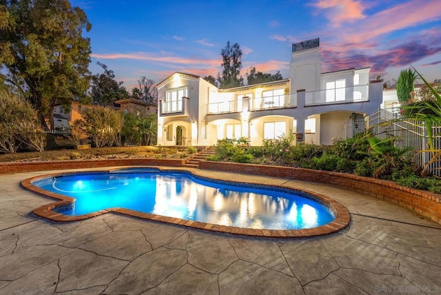 pool at dusk with a hot tub and a patio area